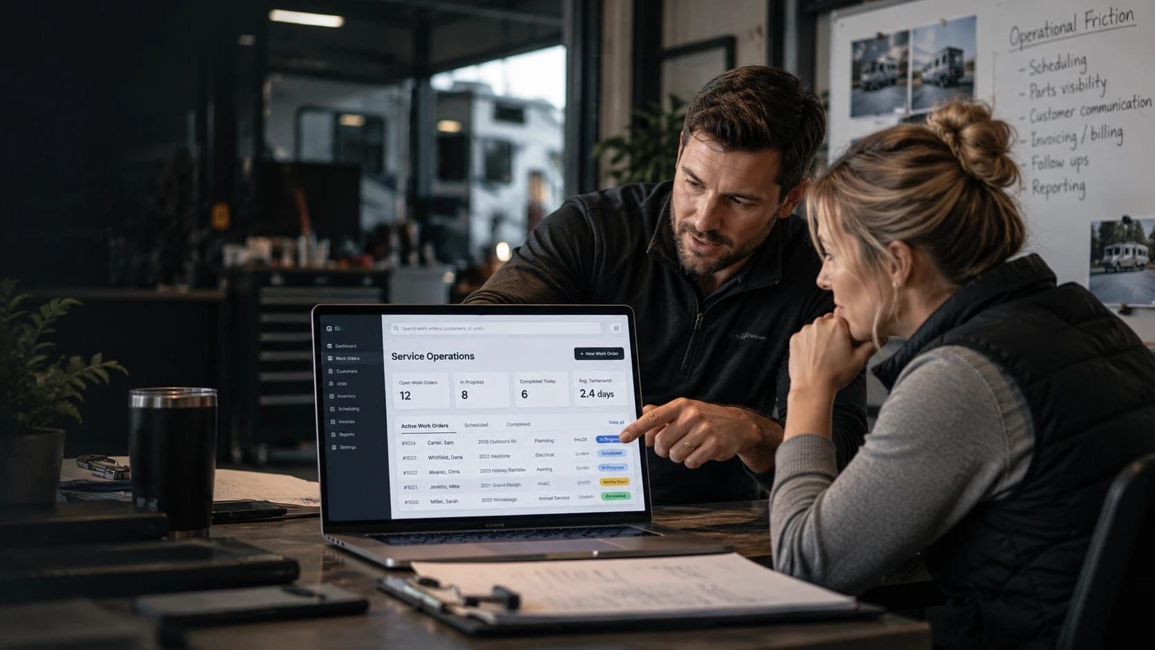 A service business owner and an advisor at a shop table reviewing a work-order dashboard, beside a whiteboard listing operational friction: scheduling, parts visibility, customer communication, invoicing, follow-ups, reporting.